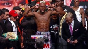 Profbokser Floyd Mayweather Jr op de weegschaal tijdens officiële weging voorafgaand aan een wedstrijd, omringd door teamleden en media – symbool voor de rol van voeding, gewicht en voorbereiding in de bokssport.