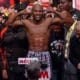 Profbokser Floyd Mayweather Jr op de weegschaal tijdens officiële weging voorafgaand aan een wedstrijd, omringd door teamleden en media – symbool voor de rol van voeding, gewicht en voorbereiding in de bokssport.